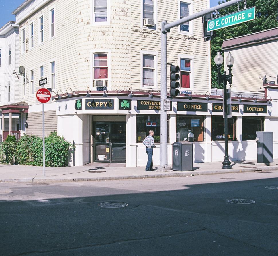 Free Image of Convenience store in neighborhood with street sign and pedestrian activity 