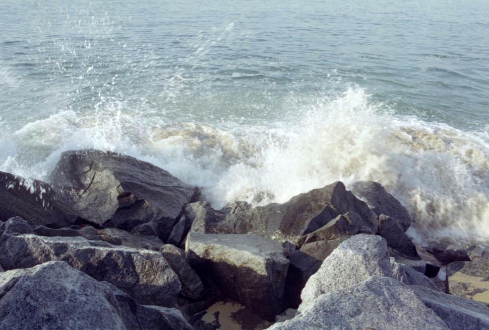 Free Image of Waves crashing against rocks along a serene coastline during daylight hours 