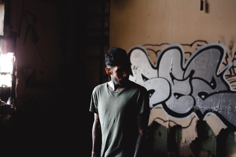 Free Image of Urban exploration by a man with tattoos in a graffiti-covered building 