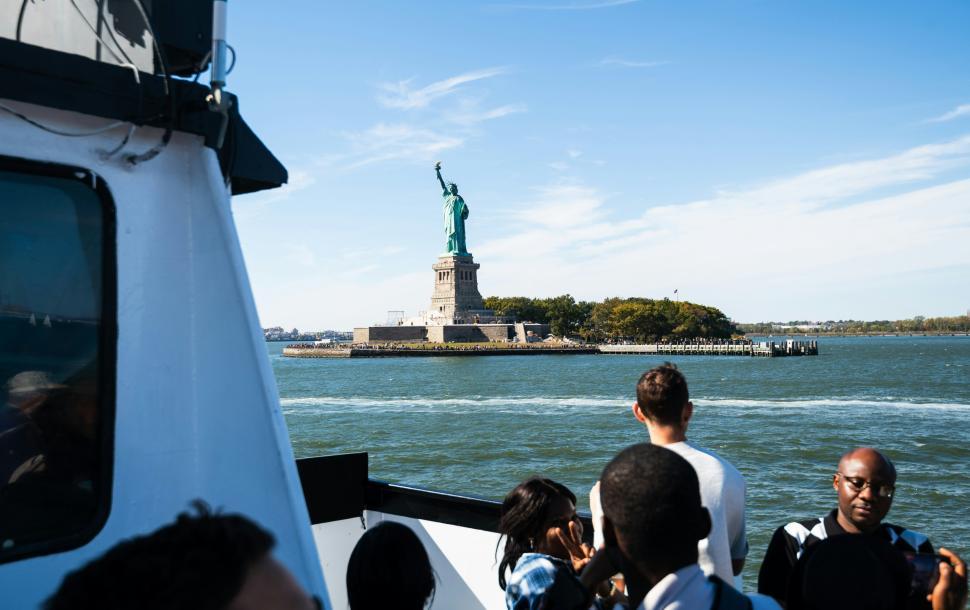Free Image of Visitors admire Statue of Liberty from boat on sunny day 