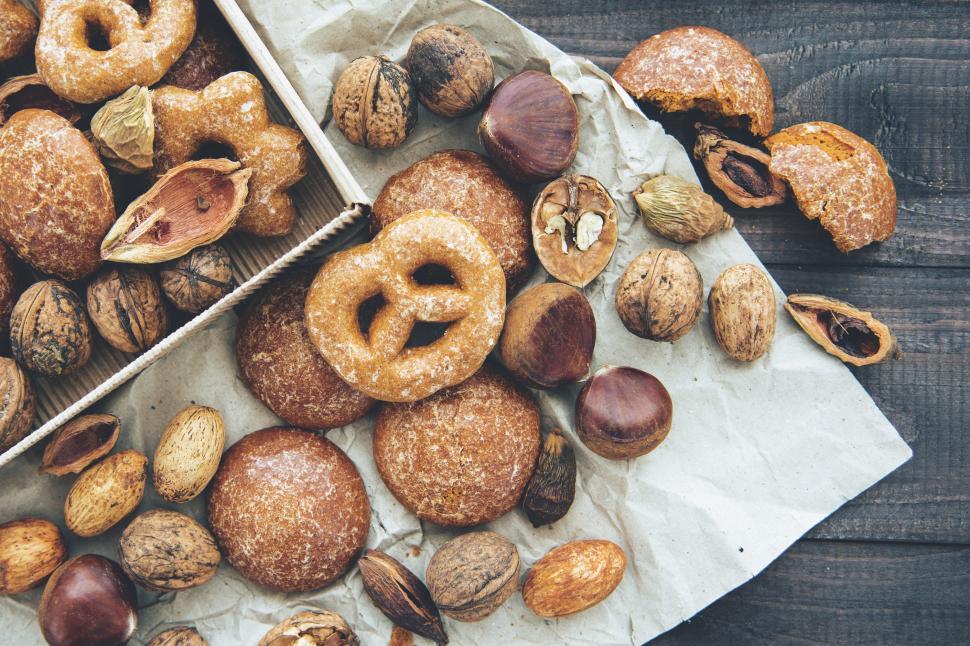 Free Image of Savory baked goods and nuts arranged on crinkled paper in a cozy kitchen setting 