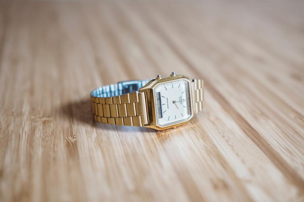 Free Image of Classic gold watch displayed on a wooden surface 