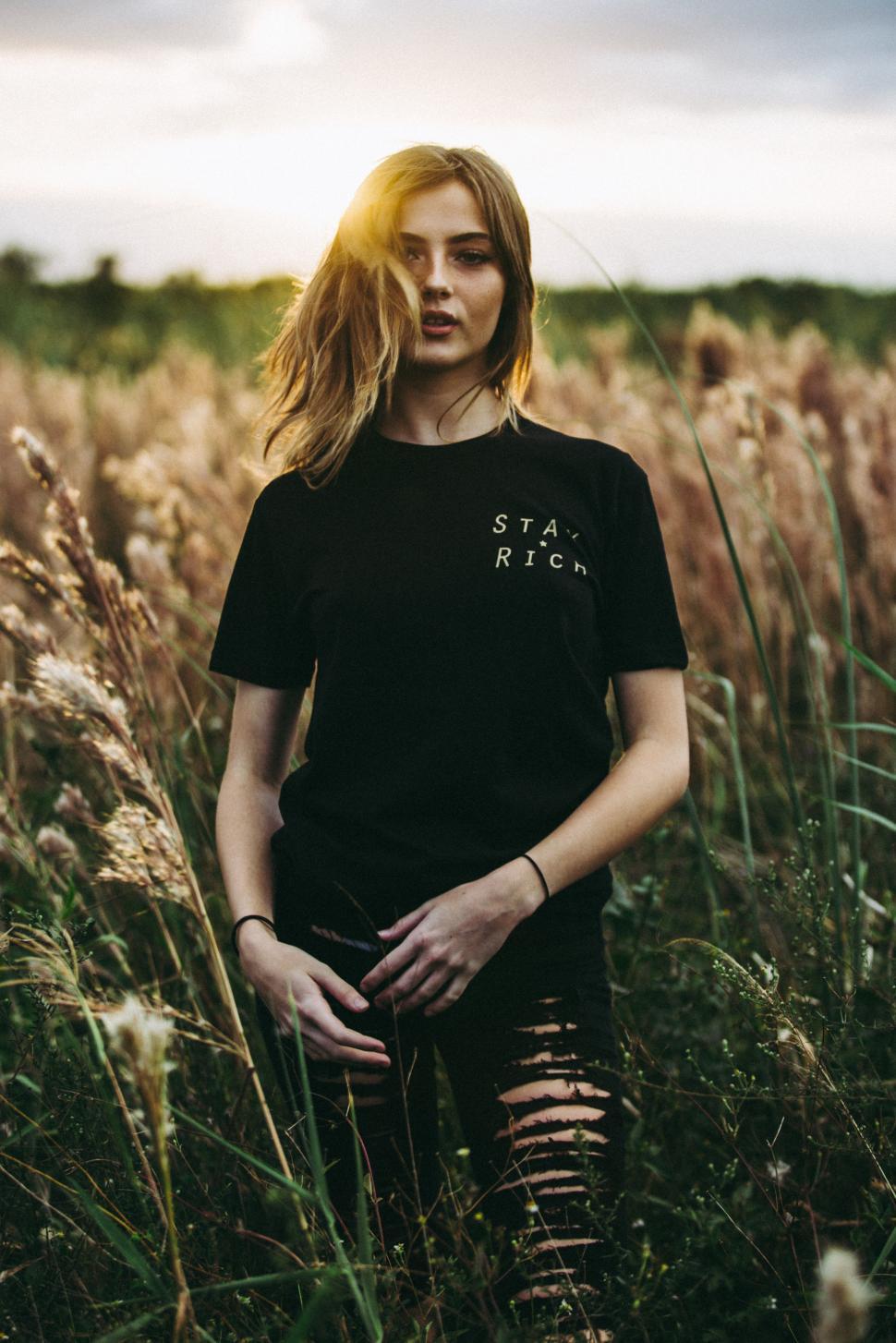 Free Image of Model poses in a sunny field wearing casual clothing during golden hour 
