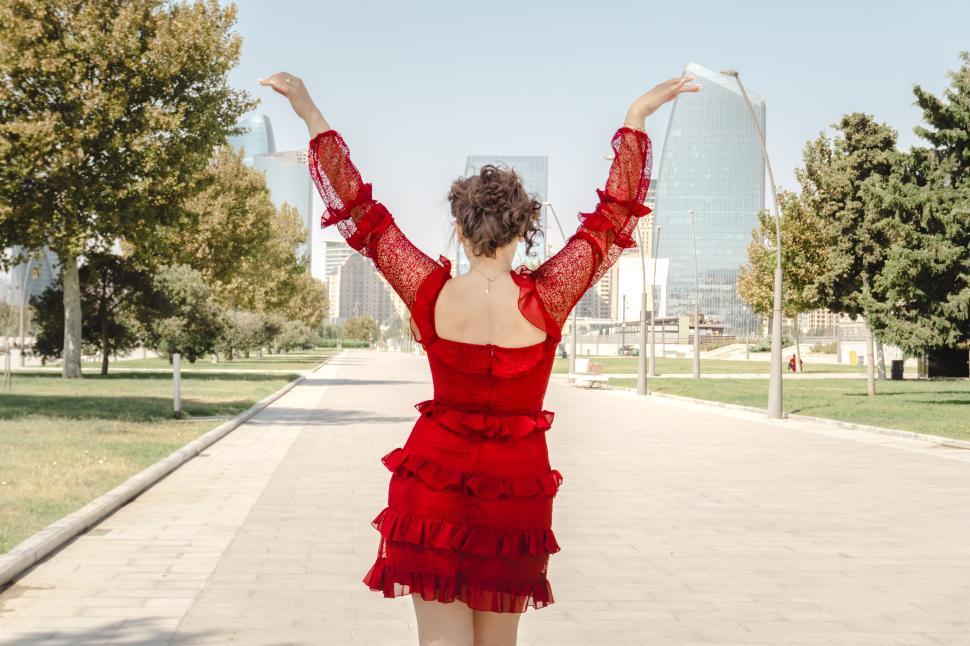 Free Image of A young woman posing confidently in a modern urban environment, showcasing contemporary fashion, natural beauty, and a vibrant city lifestyle with stylish architecture in the background.  