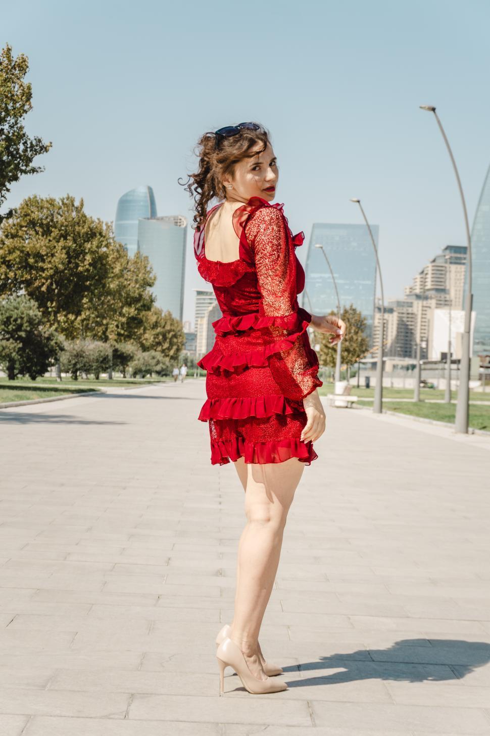 Free Image of A young woman posing confidently in a modern urban environment, showcasing contemporary fashion, natural beauty, and a vibrant city lifestyle with stylish architecture in the background.  