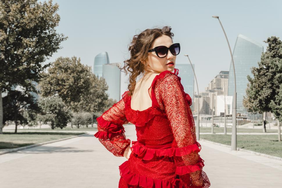Free Image of A young woman posing confidently in a modern urban environment, showcasing contemporary fashion, natural beauty, and a vibrant city lifestyle with stylish architecture in the background.  