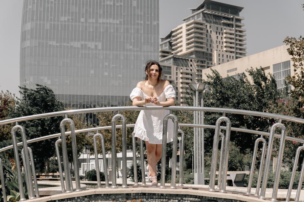 Free Image of A young woman posing confidently in a modern urban environment, showcasing contemporary fashion, natural beauty, and a vibrant city lifestyle with stylish architecture in the background.  