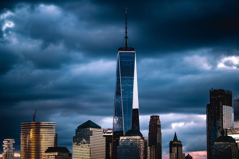 Free Image of Skyscraper reaches into stormy skies over urban landscape at dusk 
