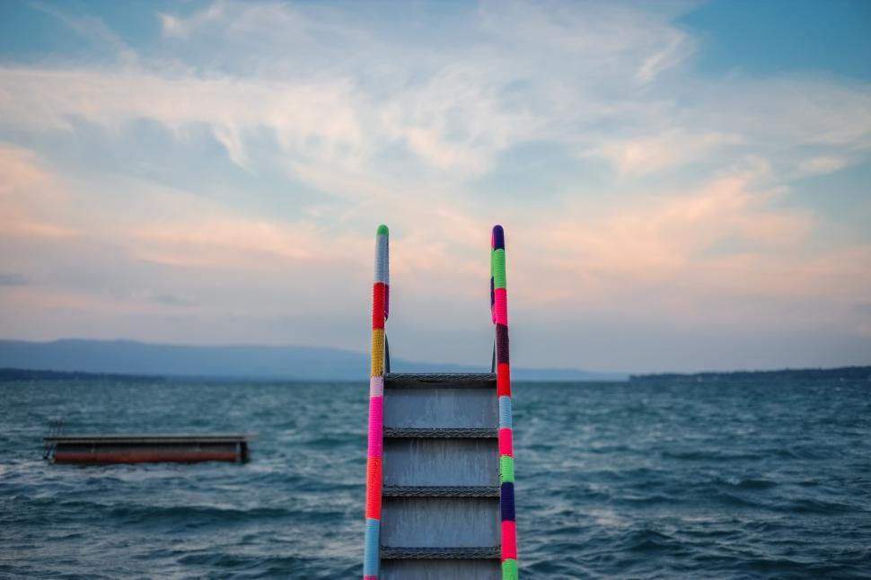Free Image of Colorful ladder leading to calm waters at dusk near a lakeside retreat 