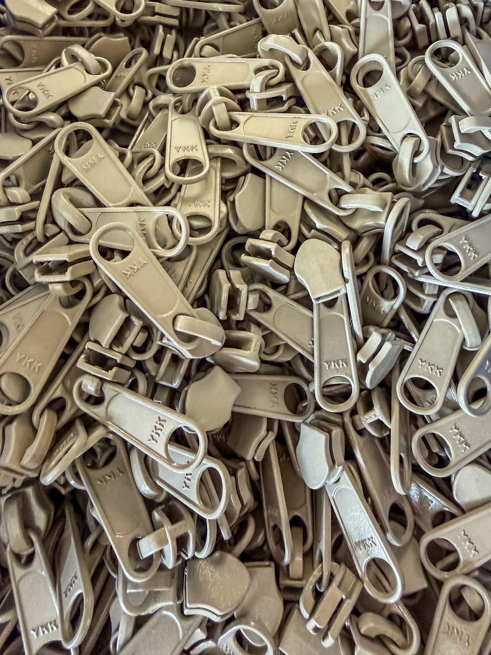 Free Image of Metal zipper pulls stacked in a large pile for manufacturing 