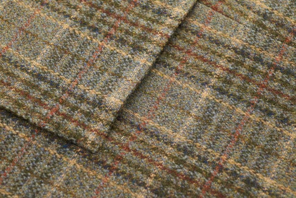 Free Image of Textured green plaid fabric with warm tones displayed on a flat surface 