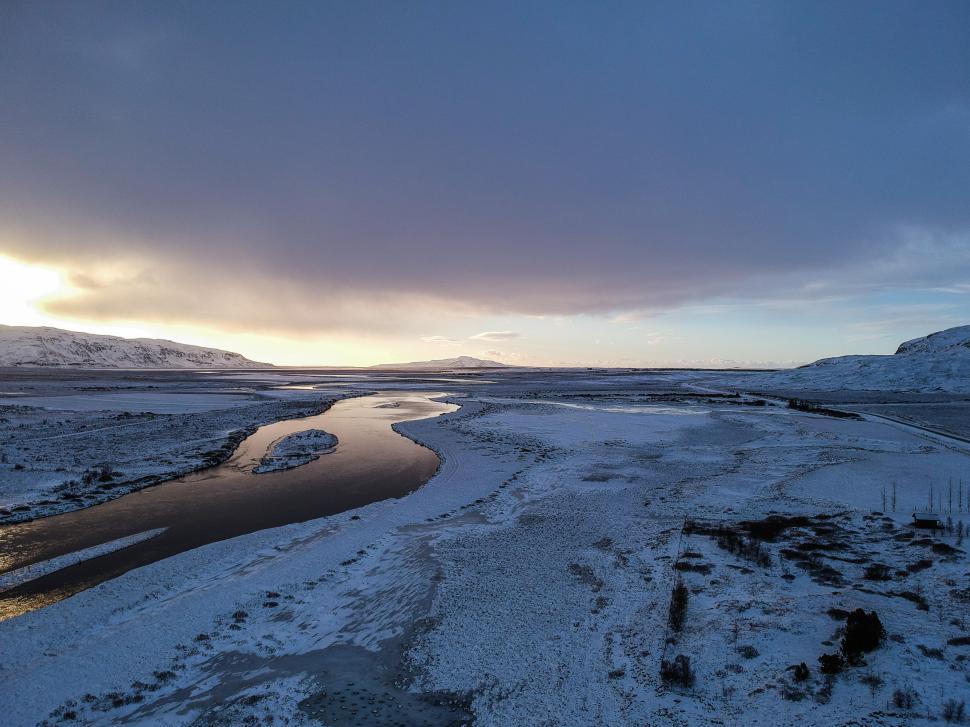 Free Image of Winter landscape featuring a winding river and snow-covered terrain in Iceland 