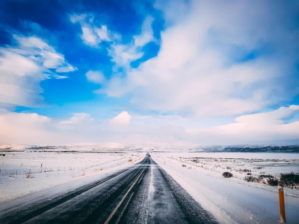Free Image of Snowy road stretches into a bright sky in a winter landscape near mountains 