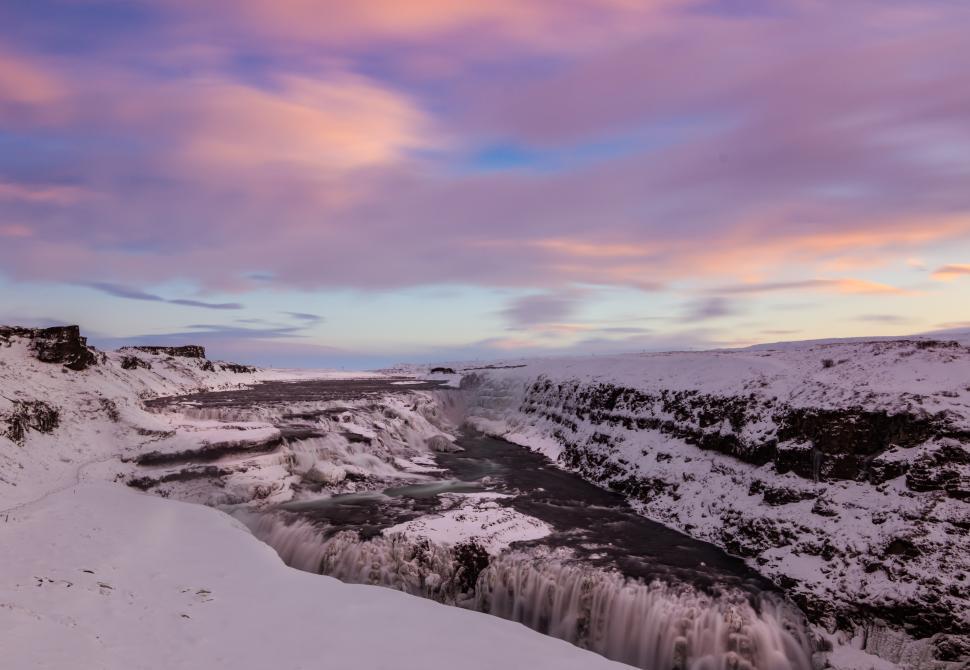 Free Image of Majestic waterfall cascading into icy river during sunset in winter landscape 