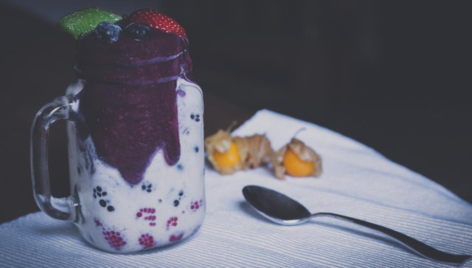 Free Image of Delicious berry smoothie in a glass with fruits and spoon on a table 
