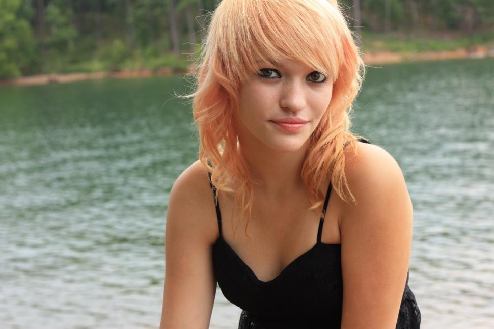 Close-up portrait of a beautiful young woman posing by a lake
