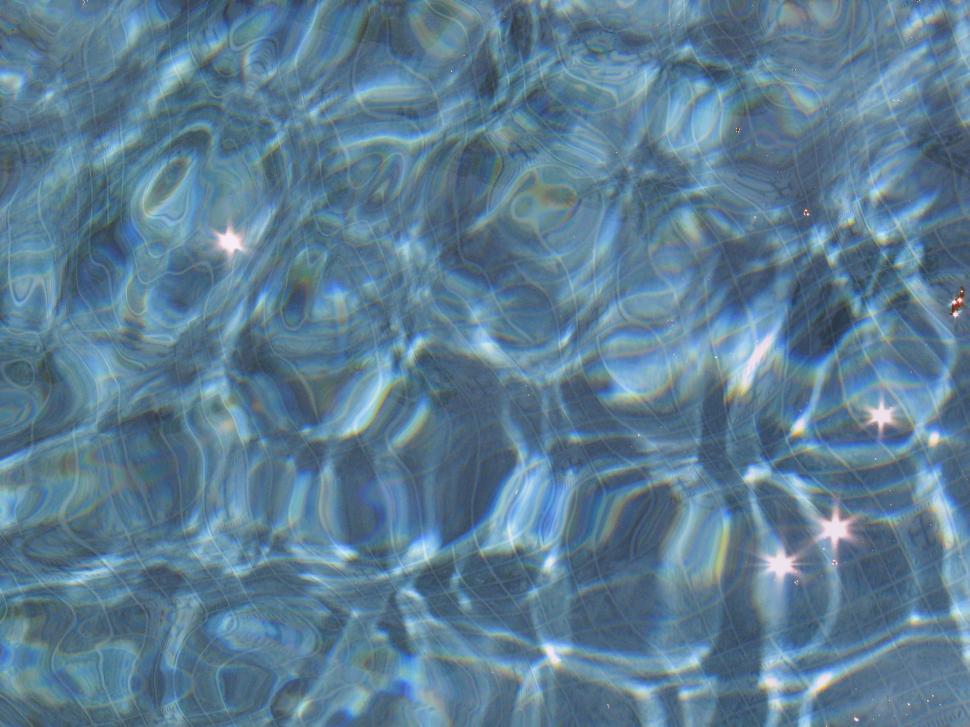 Light Blue swimming pool rippled water texture reflection. Beautiful blue  water background with glare from the sun. Stock Photo