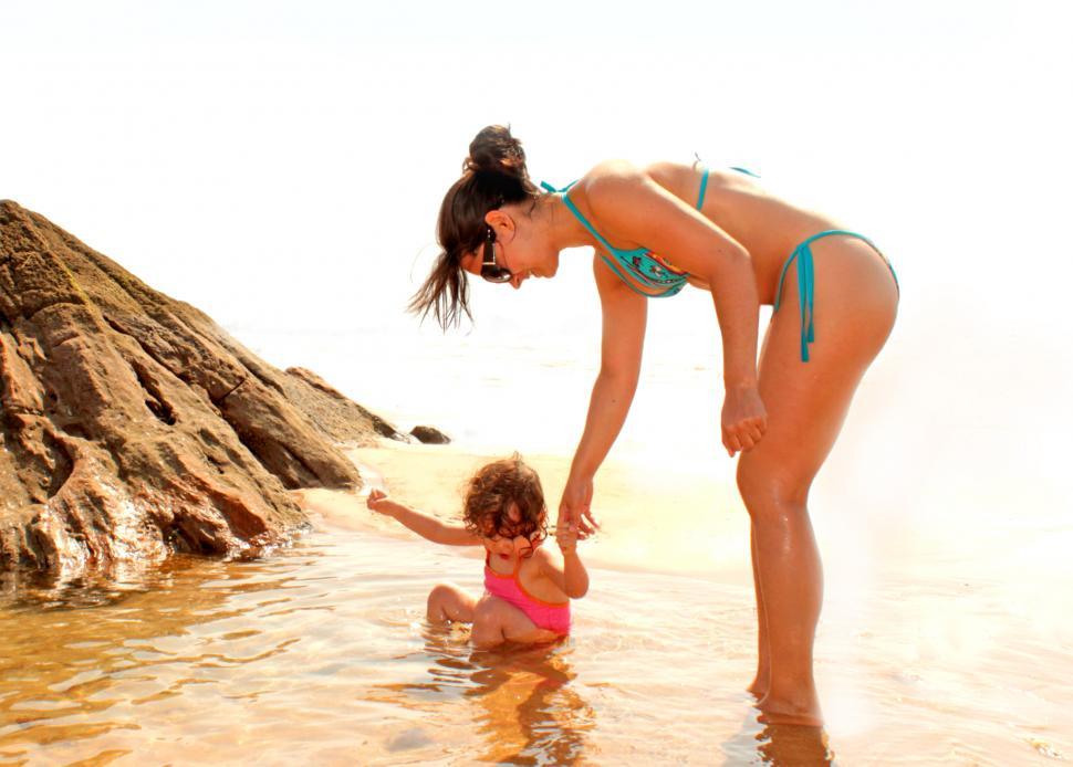 Free Image of Child bathing in a natural sea pool with the help of her mother 