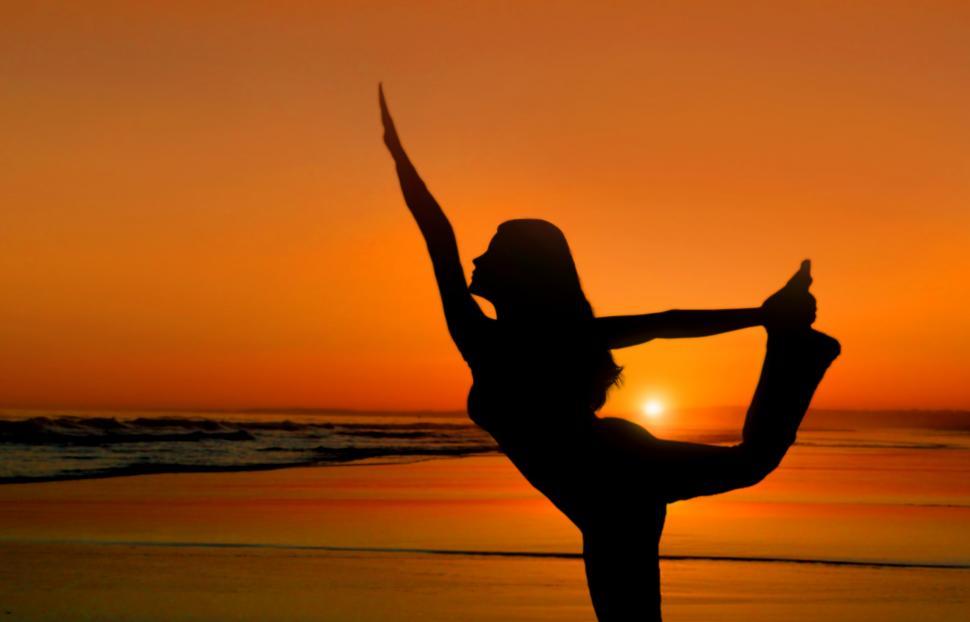 Young woman practicing yoga at beach