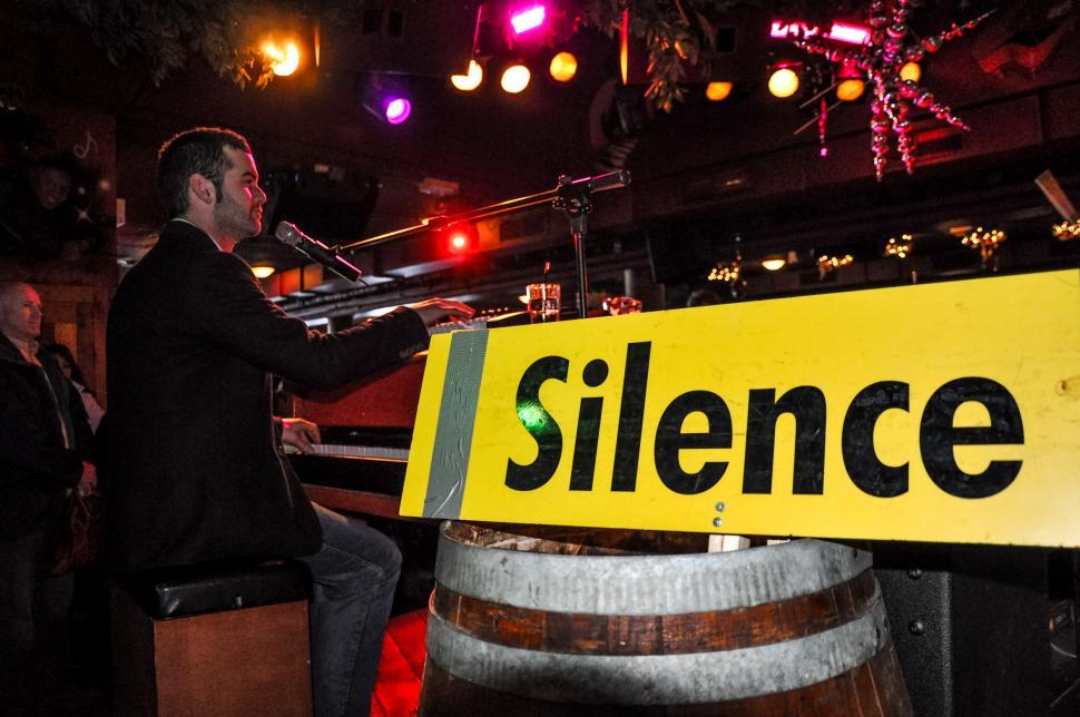 Free Image of Man Standing Next to Wooden Barrel Holding Microphone 
