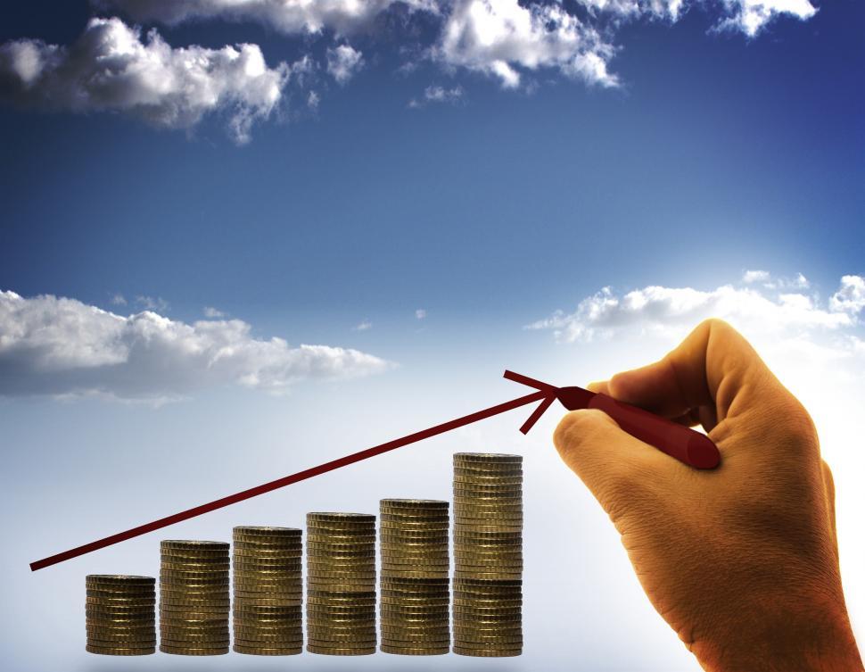 Businessman drawing an arrow over stack of coins