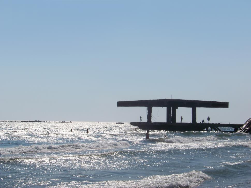 Free Image of People sitting on the ruins of the old wharf  