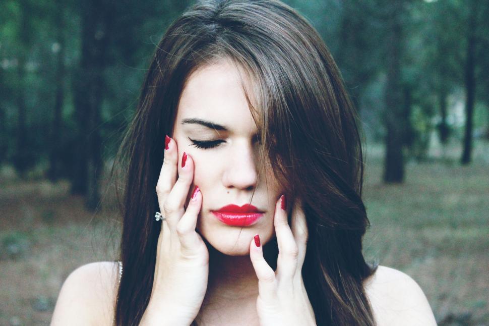 Free Image of Woman With Red Lipstick Holding Hands to Face 