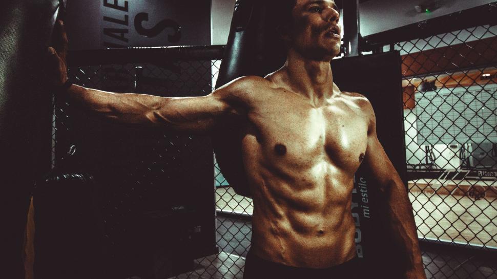 Free Image of Man Standing in Gym Holding Punching Bag 