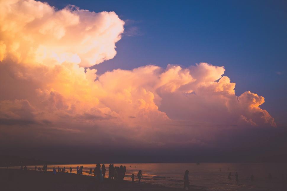 Free Image of Group of People Standing on Beach Under Cloudy Sky 