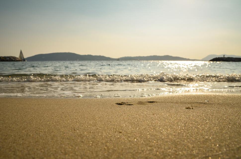 Free Image of Sandy Beach With Sailboat in Distance 