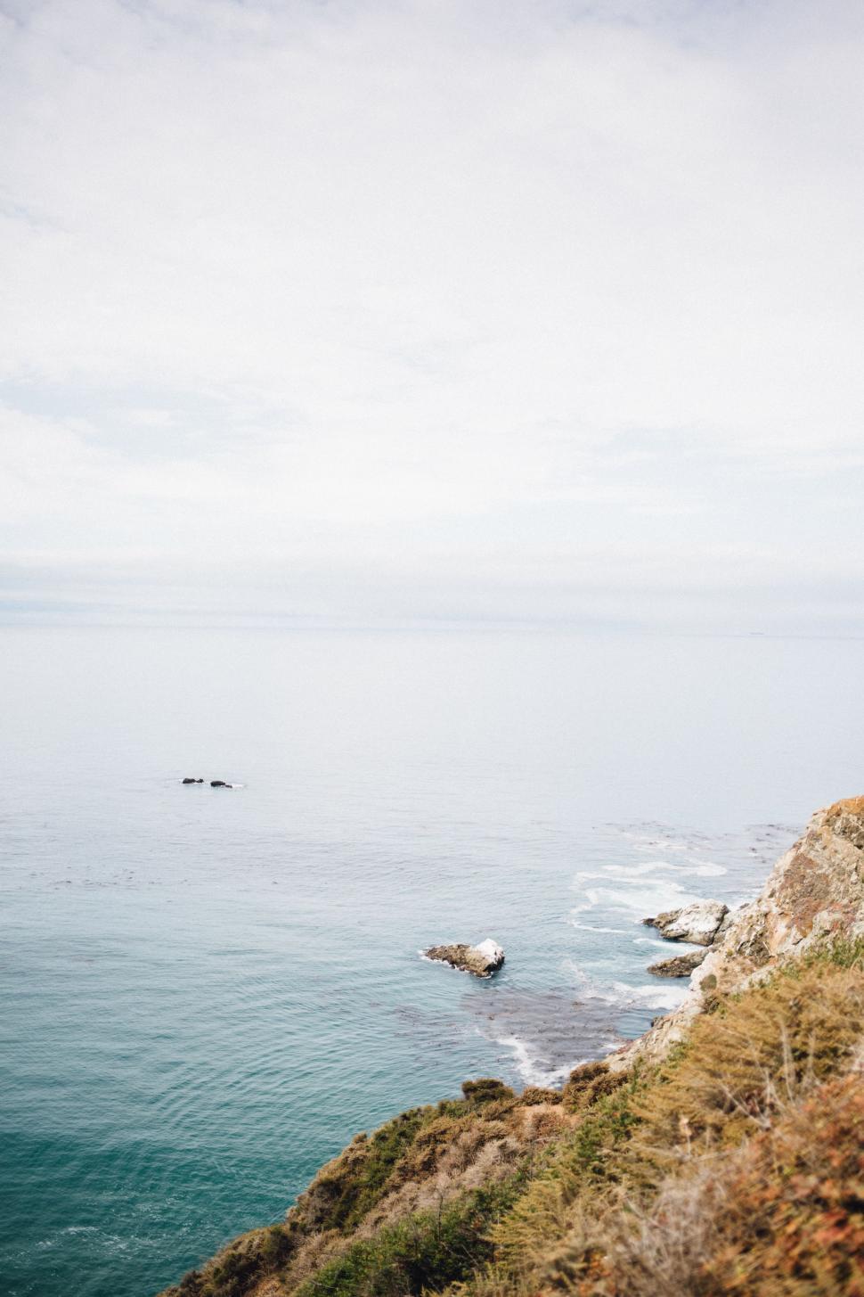 Free Image of Man Standing on Cliff Next to Ocean 
