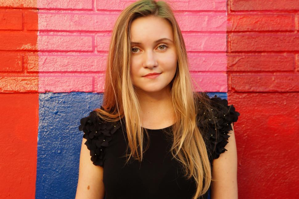 Free Image of Woman Standing in Front of Colorful Wall 