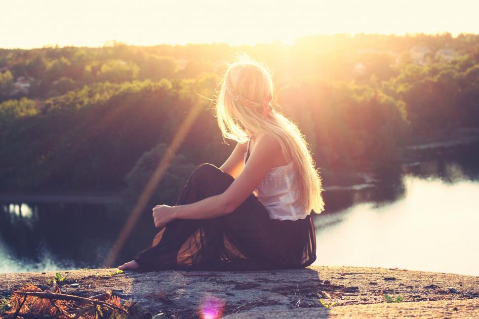 Free Image of Woman Sitting on Rock by Lake 