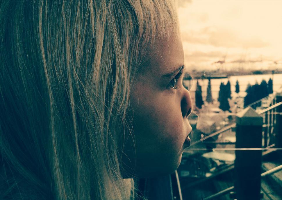 Free Image of Woman Looking Out a Window at a City 