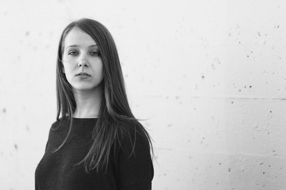 Free Image of Woman Standing in Front of White Wall 