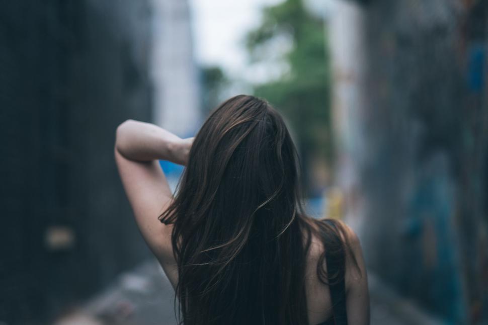 Free Image of Woman Walking Down a Street Next to Tall Buildings 