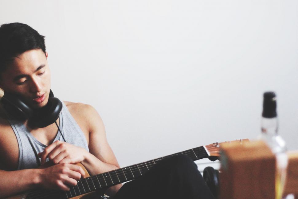 Free Image of Man Sitting on Couch Holding Guitar 