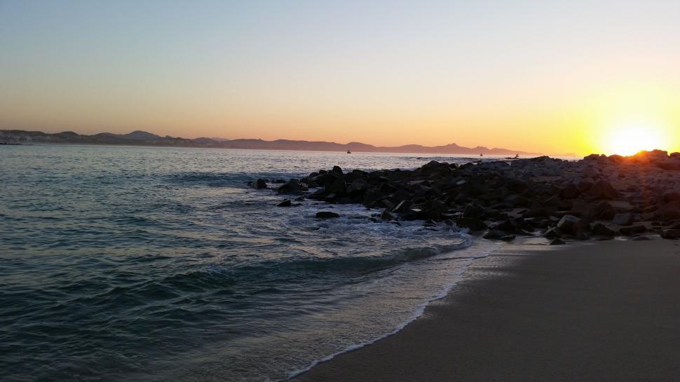 Free Image of Sun Setting Over Water at Beach 