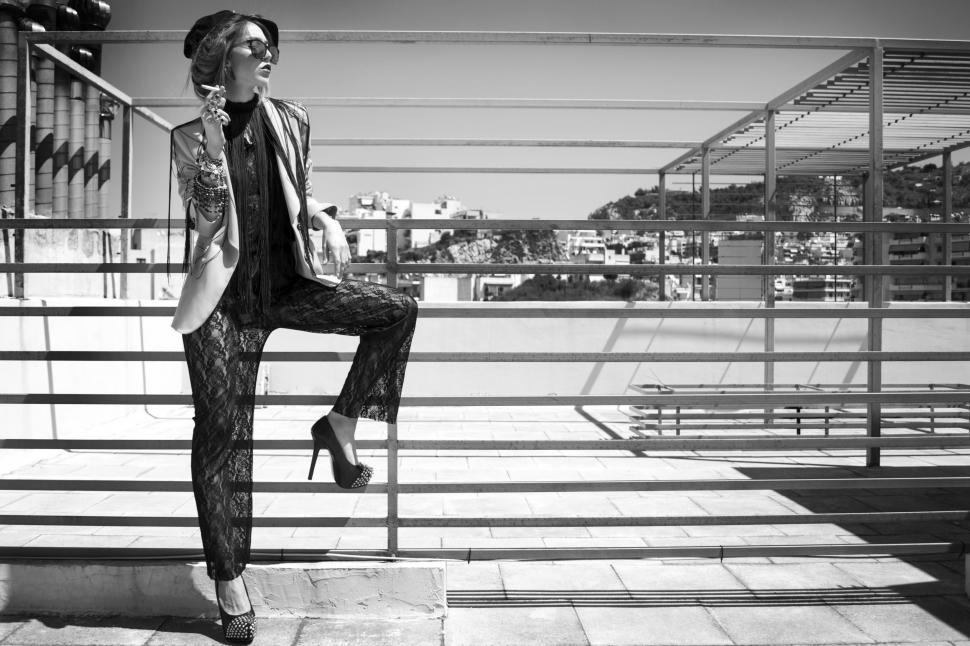 Free Image of Woman Sitting on Rail With Crossed Legs 