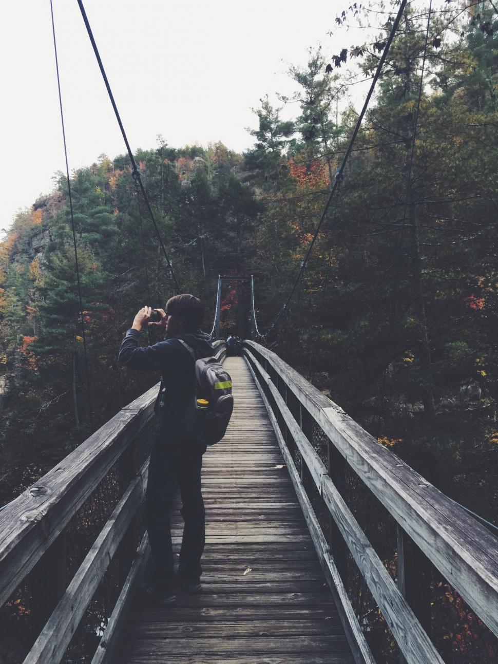 Free Image of Person Walking Across Wooden Bridge Over Water 