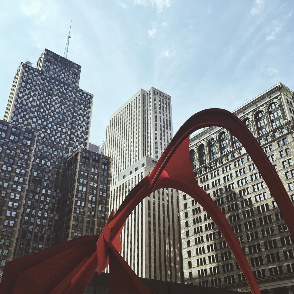 Free Image of Large Red Sculpture Standing in Front of Tall Buildings 