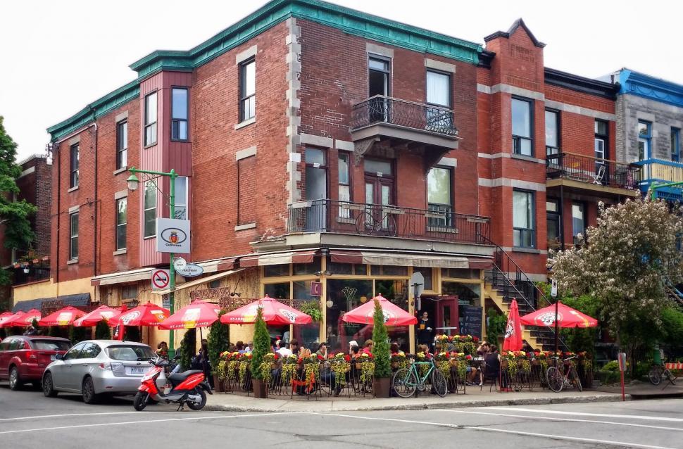 Free Image of Red Brick Building With Red Umbrellas on Street Corner 