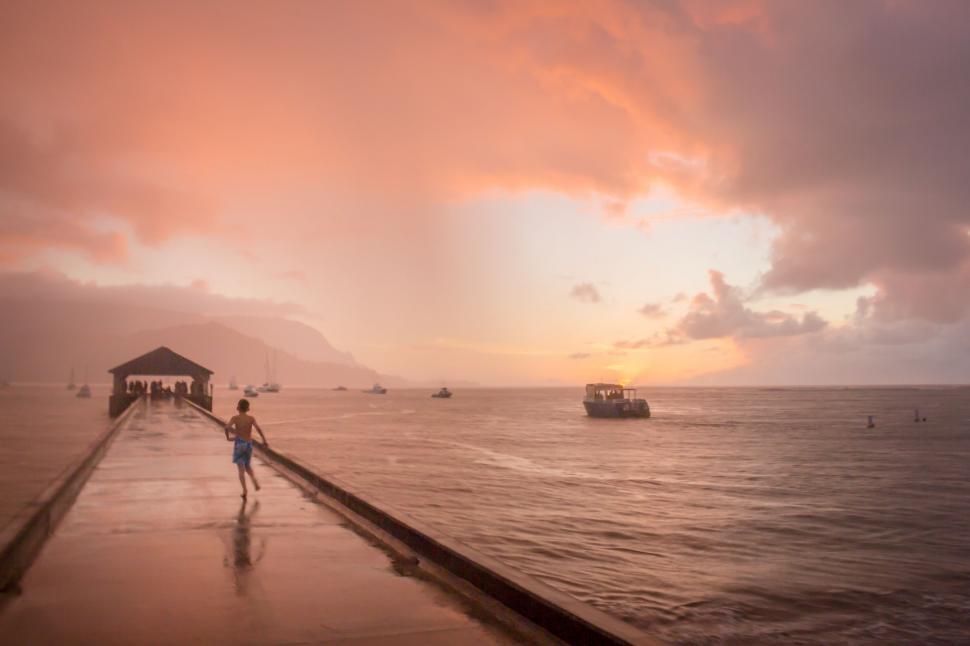 Free Image of Person Walking Along Pier With Boat in Background 