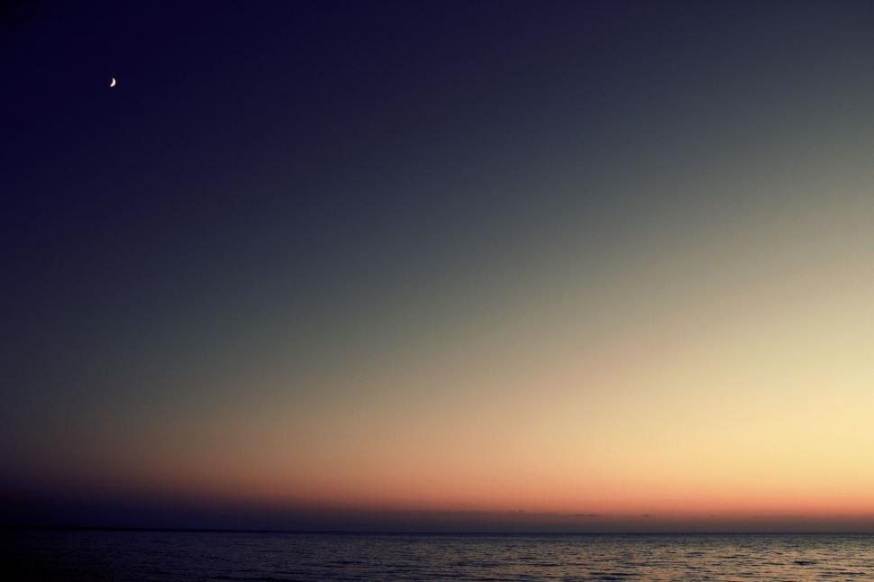 Free Image of Person Standing on Surfboard in Ocean at Sunset 