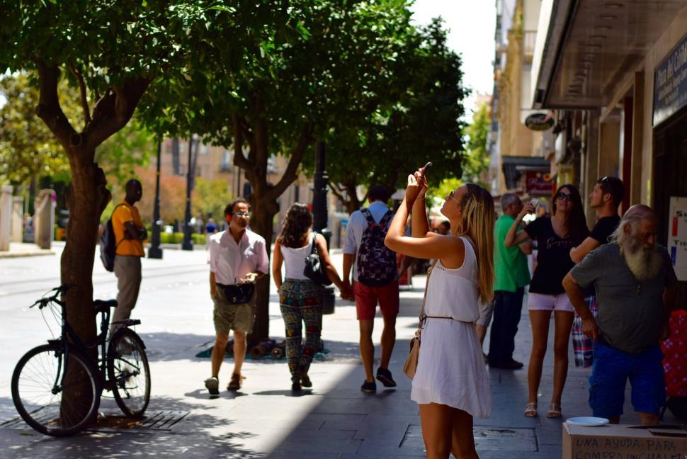 Free Image of Group of People Standing on Sidewalk Next to Tree 