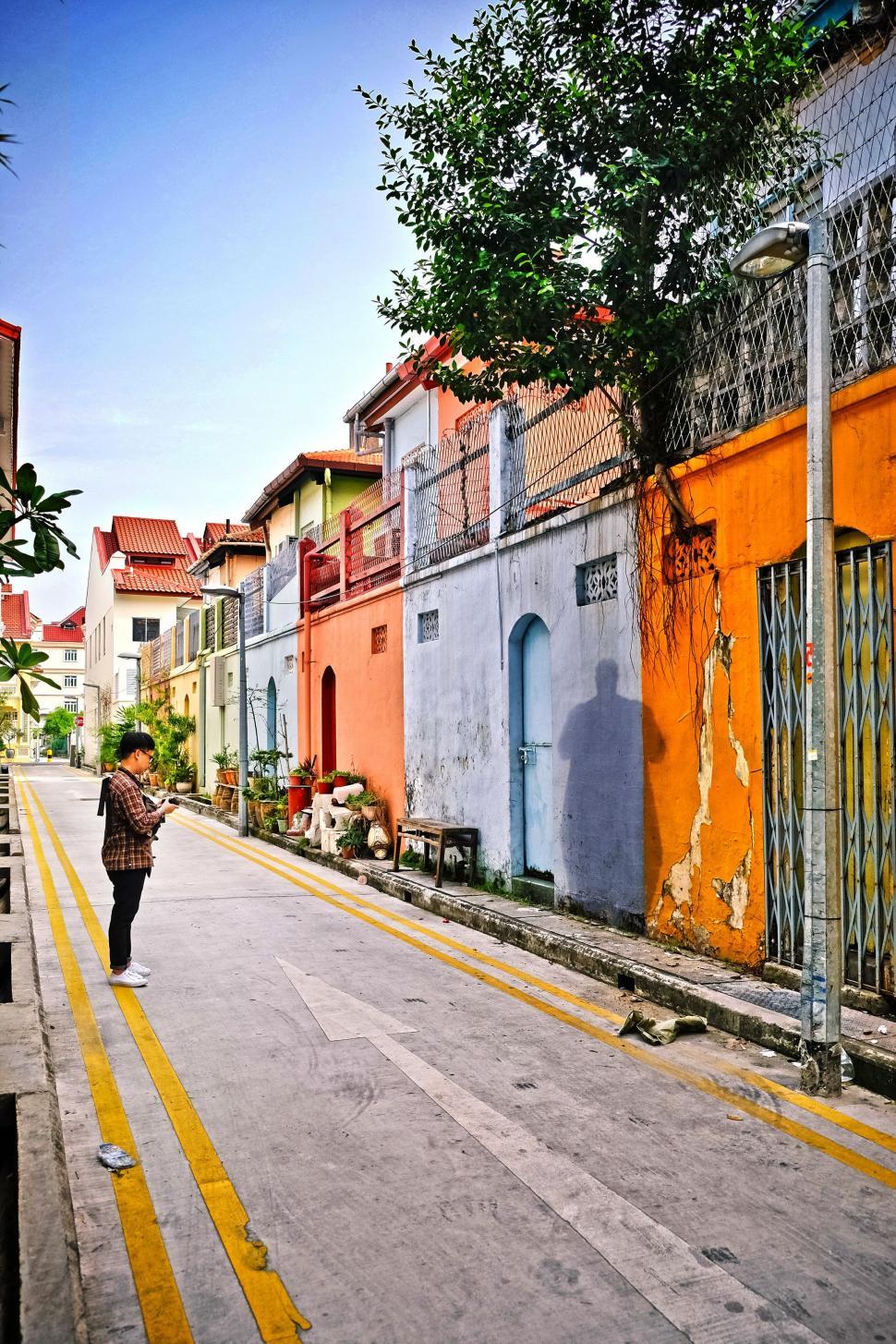 Free Image of Man Walking Down Urban Street Next to Tall Buildings 