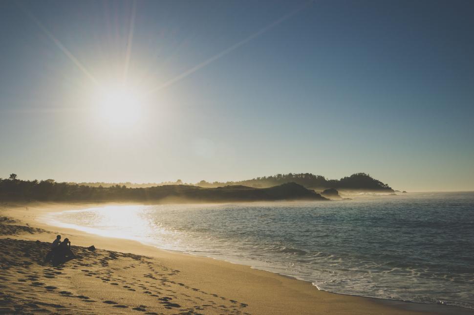 Free Image of Person Sitting on Beach Next to Ocean 
