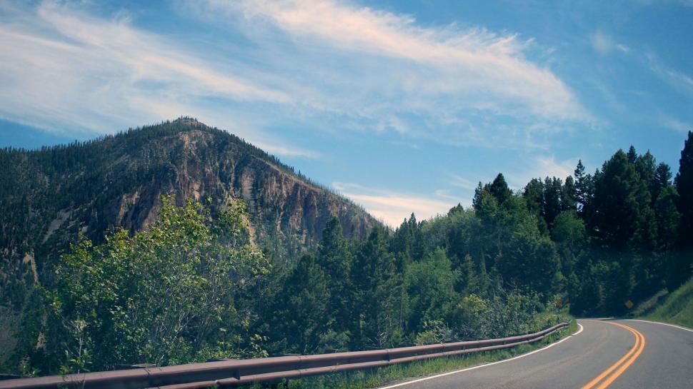 Free Image of Car Driving Down Road With Mountain in Background 