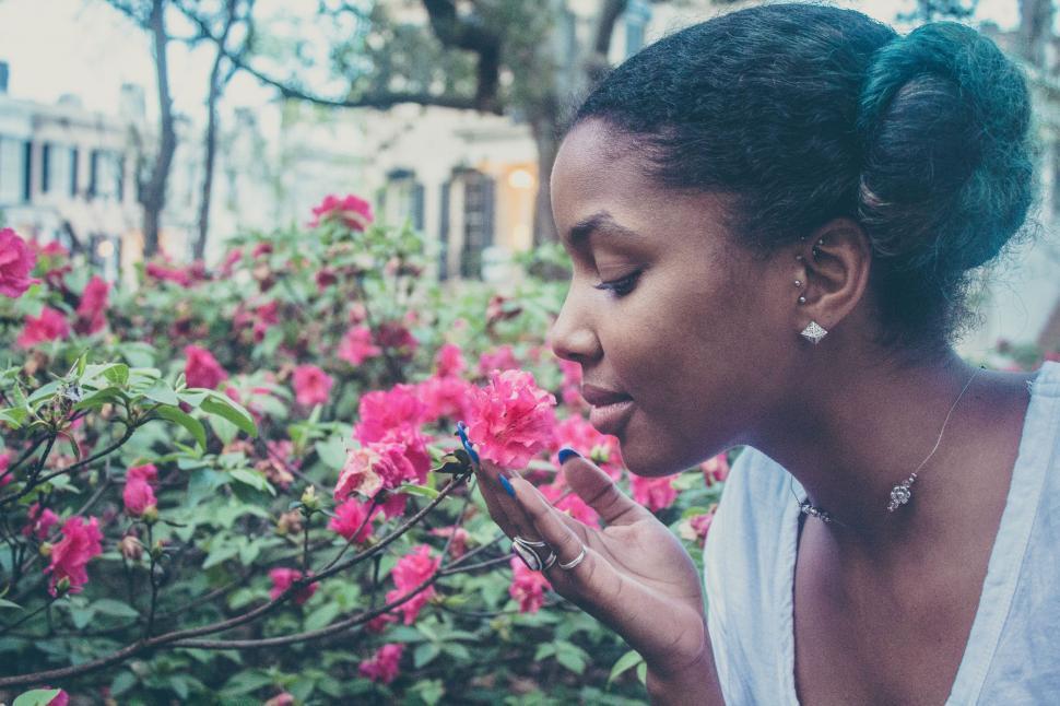 Free Image of Woman Standing in Front of a Bush of Flowers 