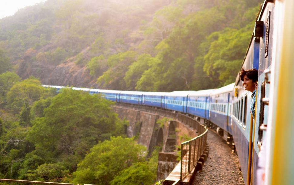 Free Image of Blue and White Train Traveling Through Lush Green Forest 